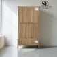A tall wooden storage cabinet with two upper doors and a lower drawer, shown in a minimalist room with a white wall and gray floor. The cabinet has a natural oak finish with visible wood grain.

