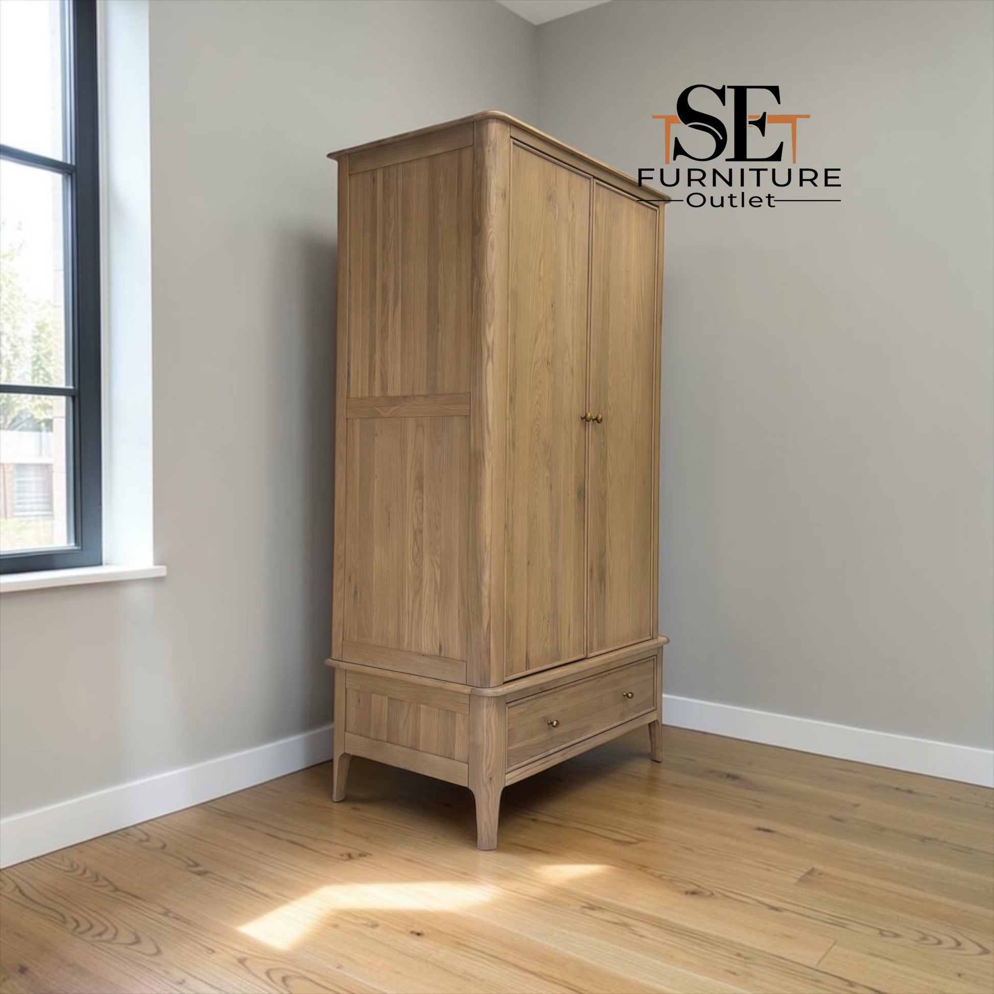 A tall two-door wooden wardrobe in a natural oak finish, positioned in a room corner with light gray walls and a wood floor. The brand logo 'SE FURNITURE Outlet' is visible in the top right corner.

