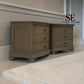 Two matching gray-brown wooden nightstands with three drawers and dark knobs, shown in a styled room setting with a white rug and gray wall molding. An 'SE FURNITURE OUTLET' logo is visible in the top right.

