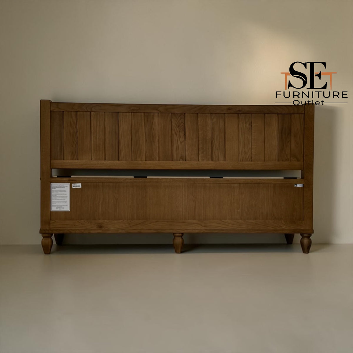 A wooden bed frame with a slatted headboard and a lower storage drawer compartment, shown against a plain beige wall. The SE Furniture Outlet logo is visible in the top right corner.

