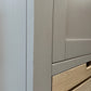 Close-up of a light gray cabinet or drawer unit with a wood-grain drawer front visible at the bottom right.

