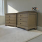 Two light oak nightstands with three drawers and dark metal knobs, shown in a styled bedroom setting with a white rug and a window.


