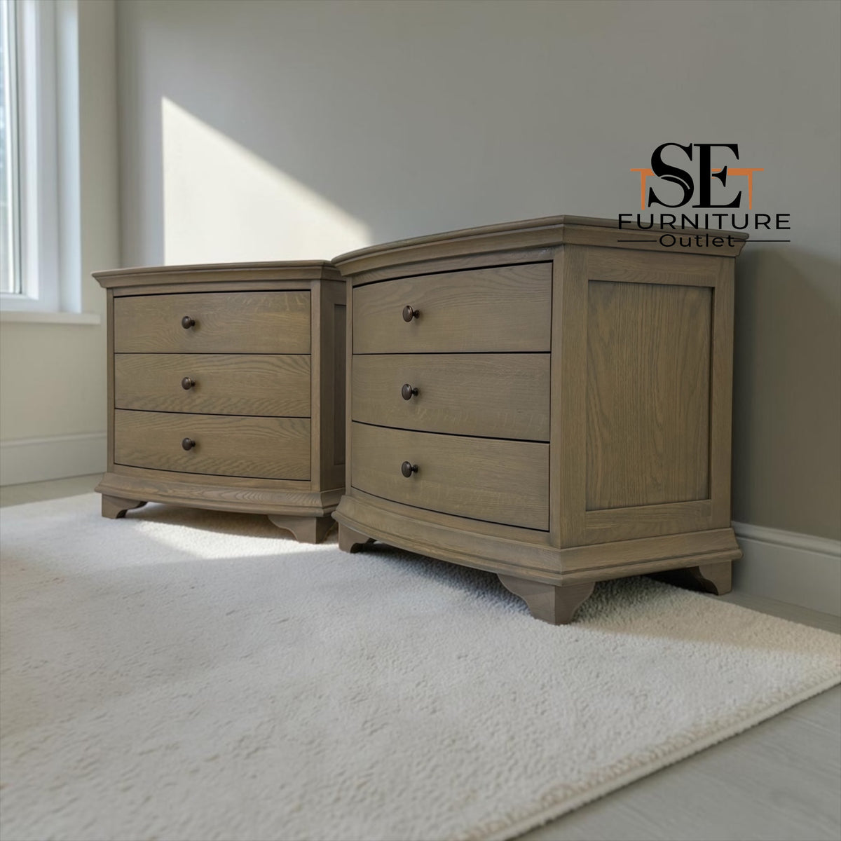 Two light oak nightstands with three drawers and dark metal knobs, shown in a styled bedroom setting with a white rug and a window.

