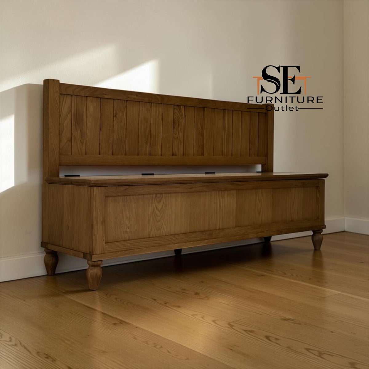 A wooden storage bench with a built-in headboard, shown in a room with light-colored walls and hardwood floors. The SE Furniture Outlet logo is visible in the upper right corner.

