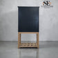 A tall black cabinet with a light natural wood base and open slatted shelf, photographed against a light gray textured wall and floor. The SE Furniture Outlet logo is visible in the top right corner.

