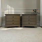 A pair of matching three-drawer nightstands in a weathered gray-brown wood finish, positioned side-by-side on a white shag rug against a paneled wall. The SE Furniture Outlet logo is visible in the upper right.

