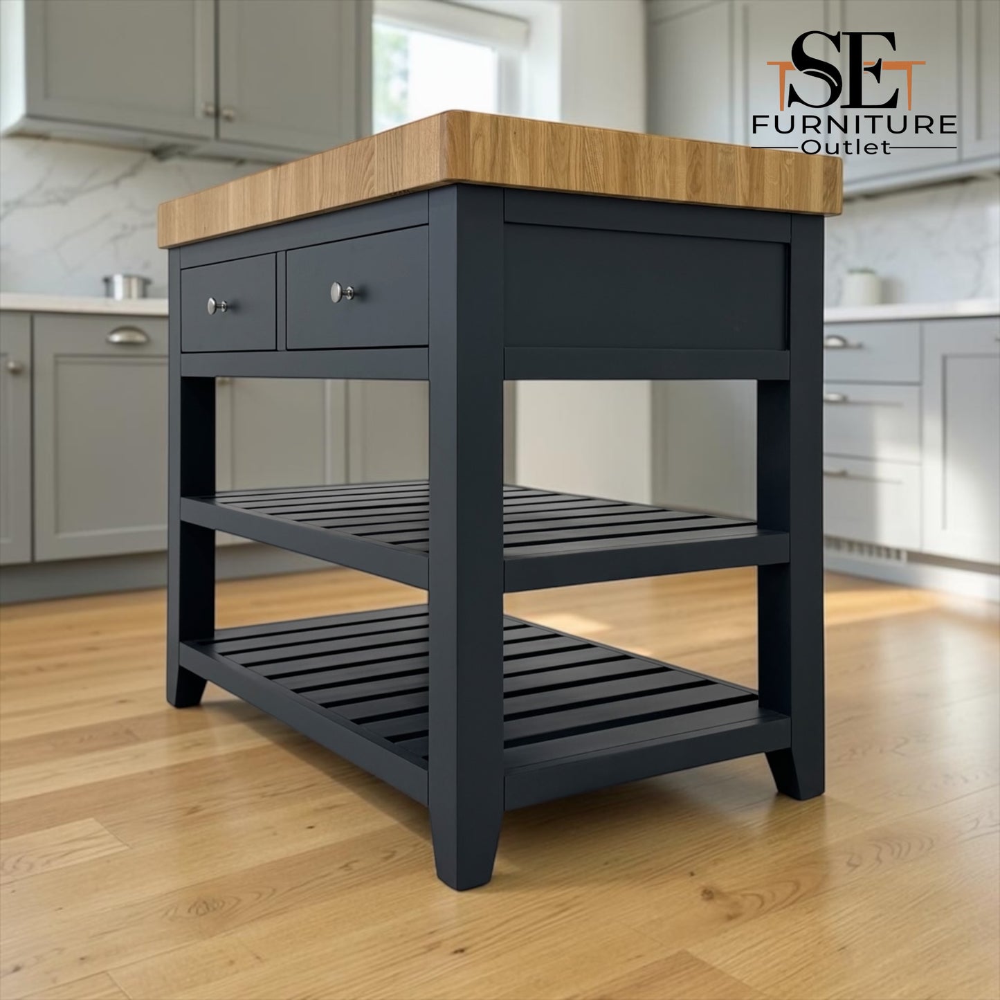A kitchen island cart with a dark charcoal gray painted frame and a natural light wood countertop, shown in a modern kitchen setting. The cart features two drawers on the upper left, two open slatted shelves, and a logo for 'SE Furniture Outlet' in the top right corner.

