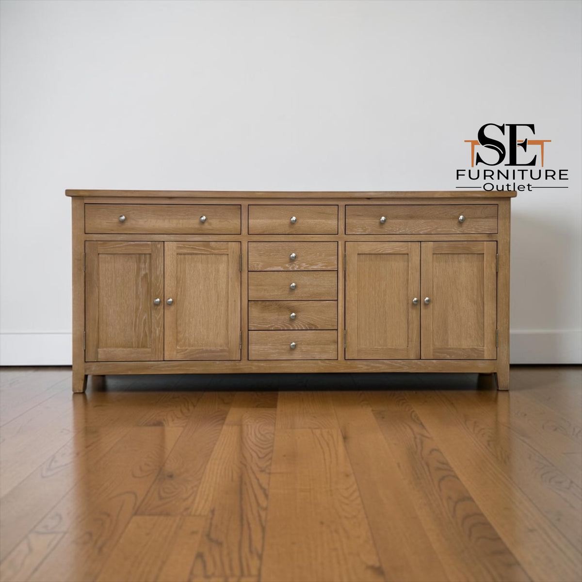 Wooden sideboard with multiple drawers and doors on a wooden floor, featuring the logo of SE Furniture Outlet.


