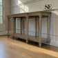 A light natural wood console table with turned legs and a lower shelf, shown in a room with hardwood floors and white paneled walls. The 'SE Furniture Outlet' logo is visible in the top right corner.

