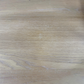 A close-up view of a light oak wood grain surface, showing natural texture and subtle variations in tone.

