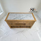A wooden console cabinet with a white and gray marble top, shown in a room with white marble floor and walls. The cabinet features three drawers on the top, an open shelf, and a slatted lower shelf.

