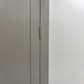 Close-up of a light gray double door with a slim gold metal hinge, set against a plain white wall.

